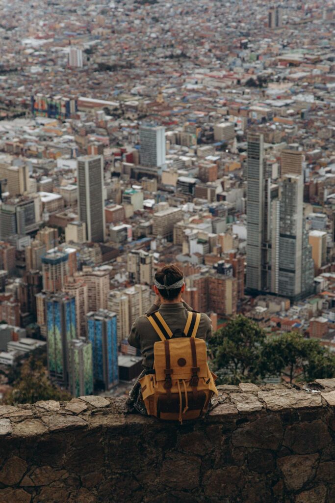 Homem sentado na mureta olhando a cidade.