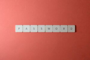 Focus on password security with white keyboard tiles spelling 'PASSWORD' on a coral background.