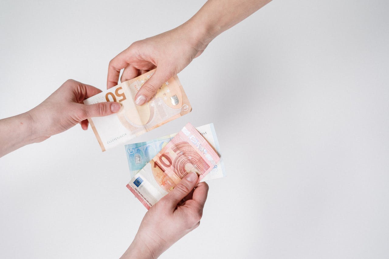 Close-up de mãos trocando cédulas de euro, simbolizando finanças e transação.