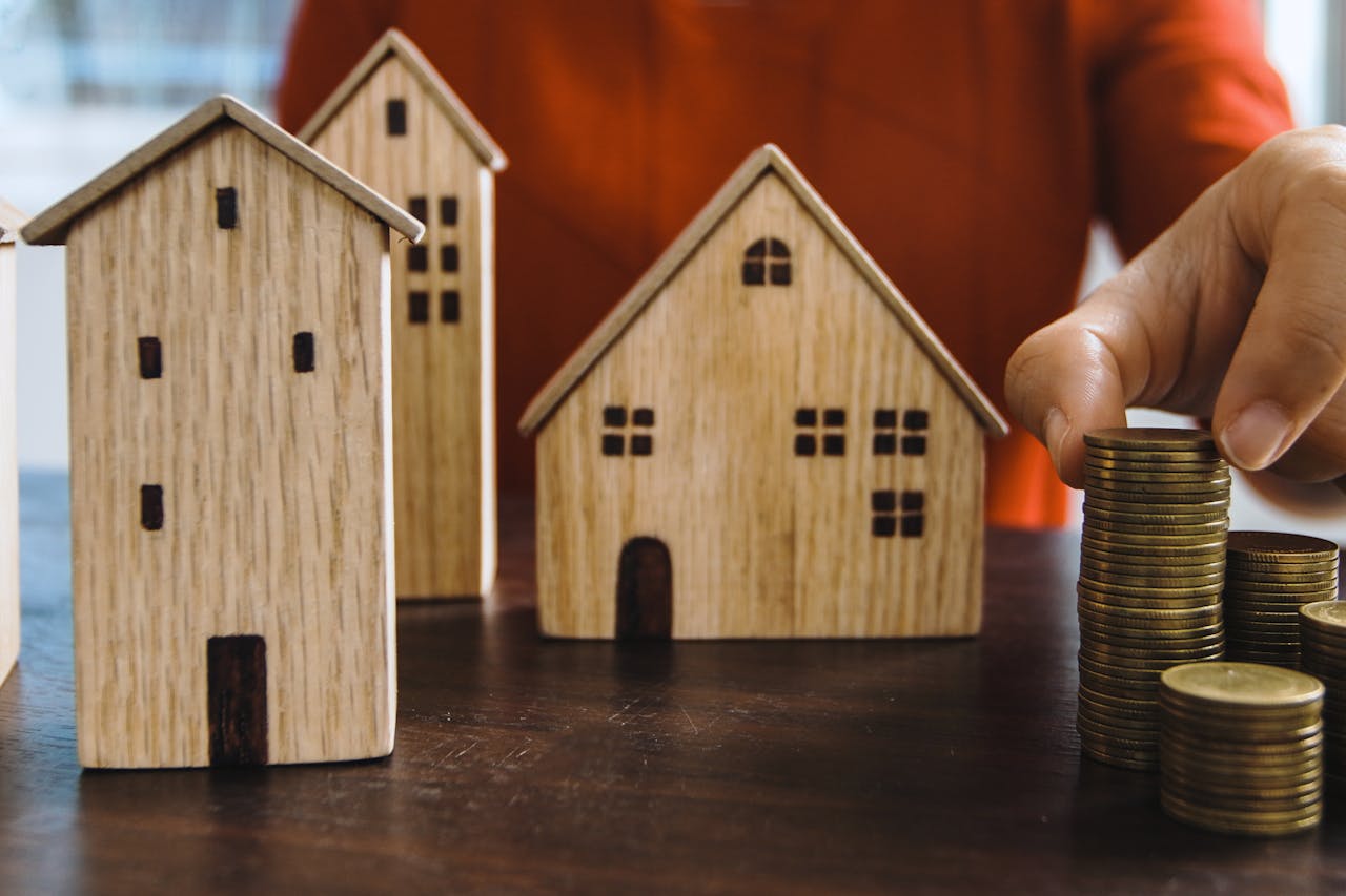 Planejando investimentos com moedas empilhadas e casas em miniatura em uma mesa.