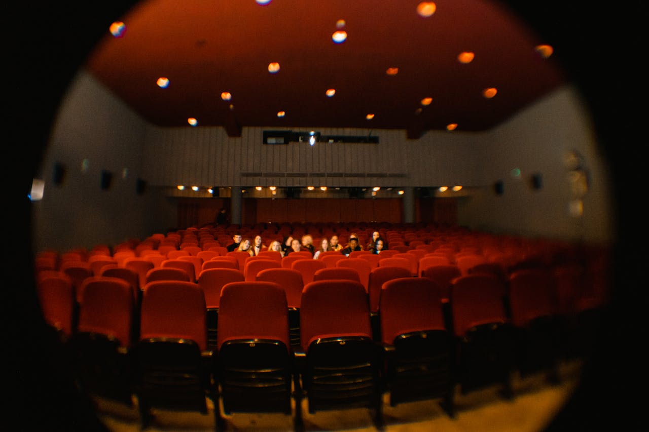 Uma lente olho de peixe captura espectadores em um cinema mal iluminado, oferecendo uma perspectiva única.