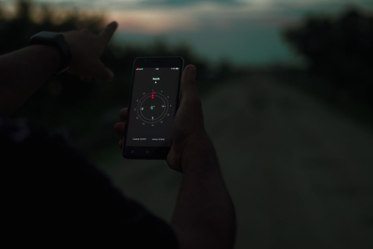 Pessoa navegando usando um aplicativo de bússola em um smartphone ao ar livre ao anoitecer.